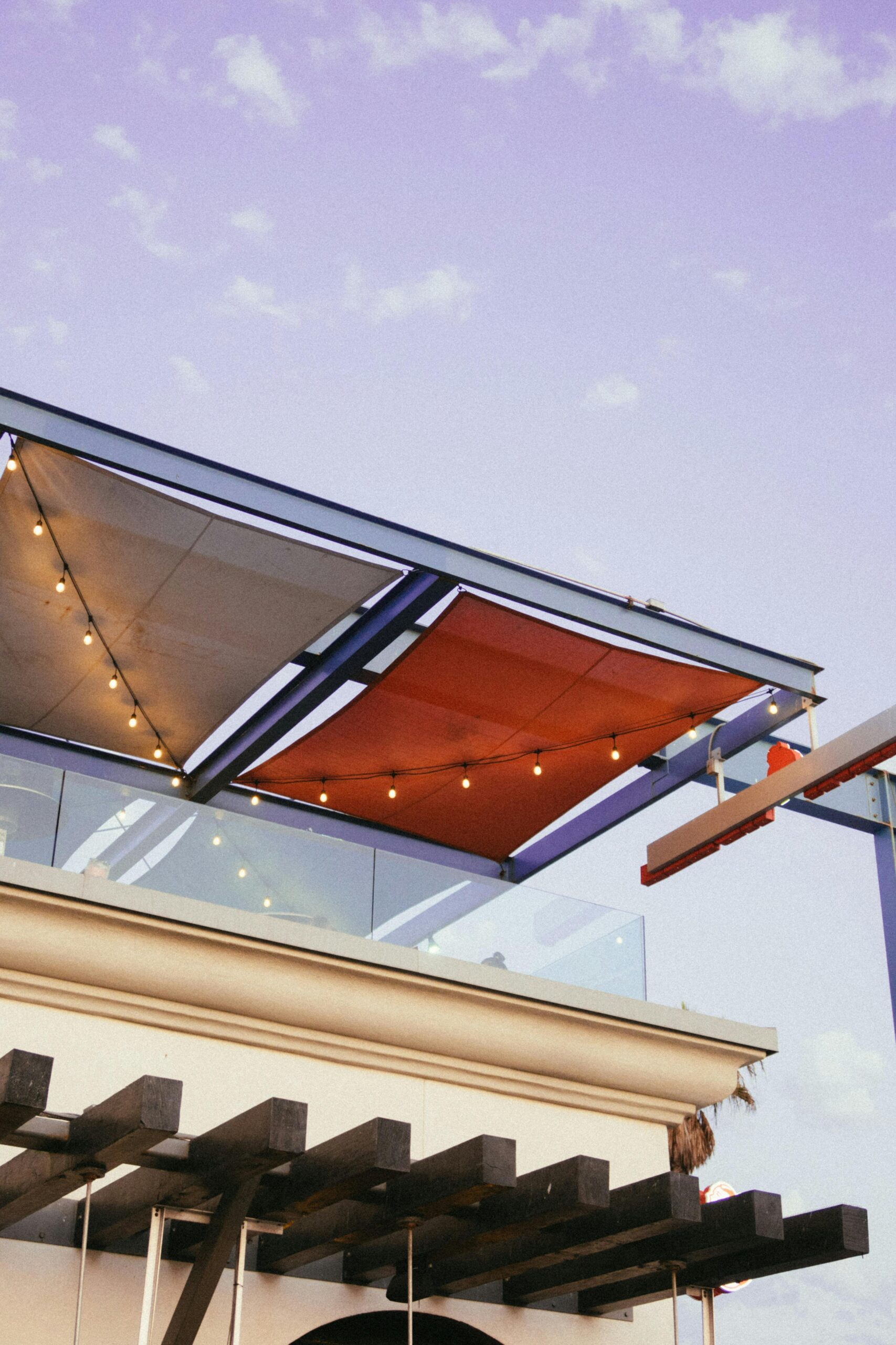 Low angle view of a modern building with colorful canopy and string lights.